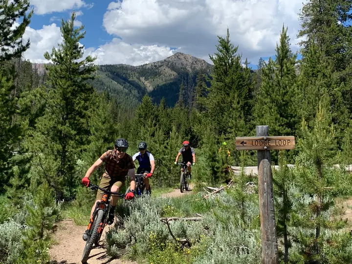 Riders on a Galena singletrack past a trail sign