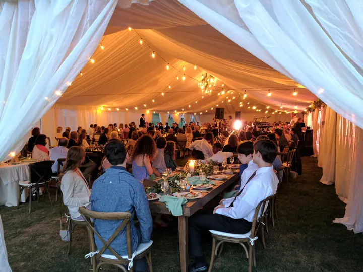 A wedding dinner under a lit tent