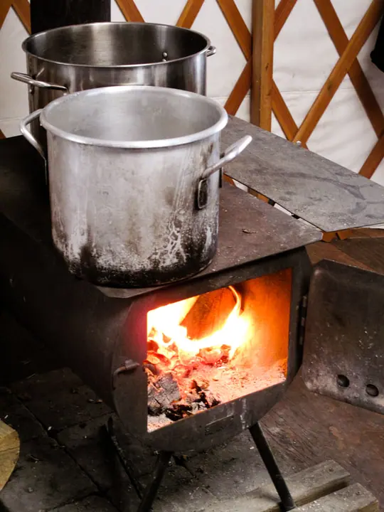 A kettle on the wood stove inside a yurt